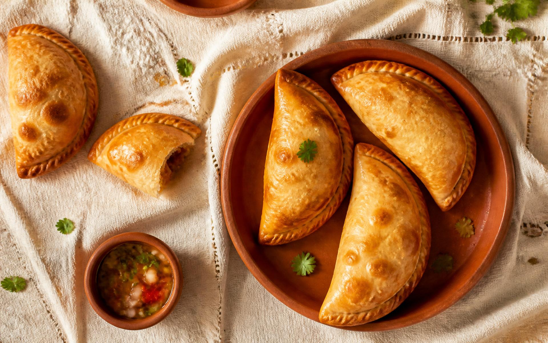 Golden baked empanadas on a terracotta plate